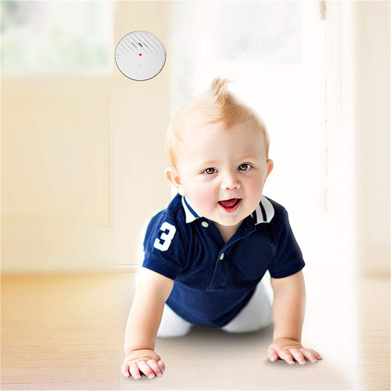 Ein Baby in blauem Hemd krabbelt auf dem Boden, darüber ein Rauchmelder.