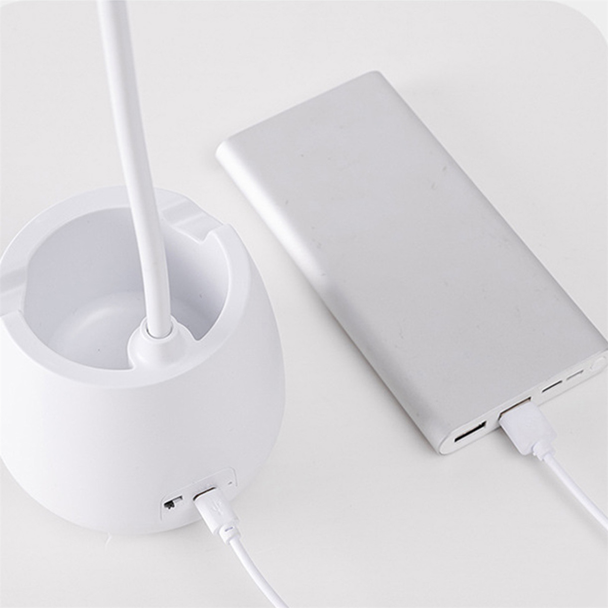 Eine weiße Lampe und eine graue Powerbank mit einem weißen Kabel. Die Lampe ist mit der Powerbank verbunden.