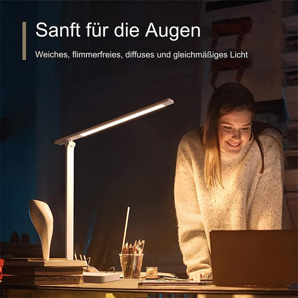 Eine Frau benutzt einen Laptop unter einer Schreibtischlampe, mit Stiften und einer Vase.