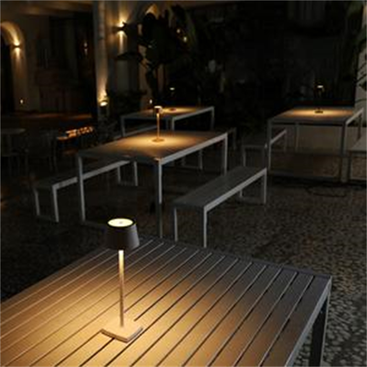 Nachtszenen mit Tischen, Bänken und Lampen. Lampen beleuchten die Tische und schaffen eine warme Atmosphäre.