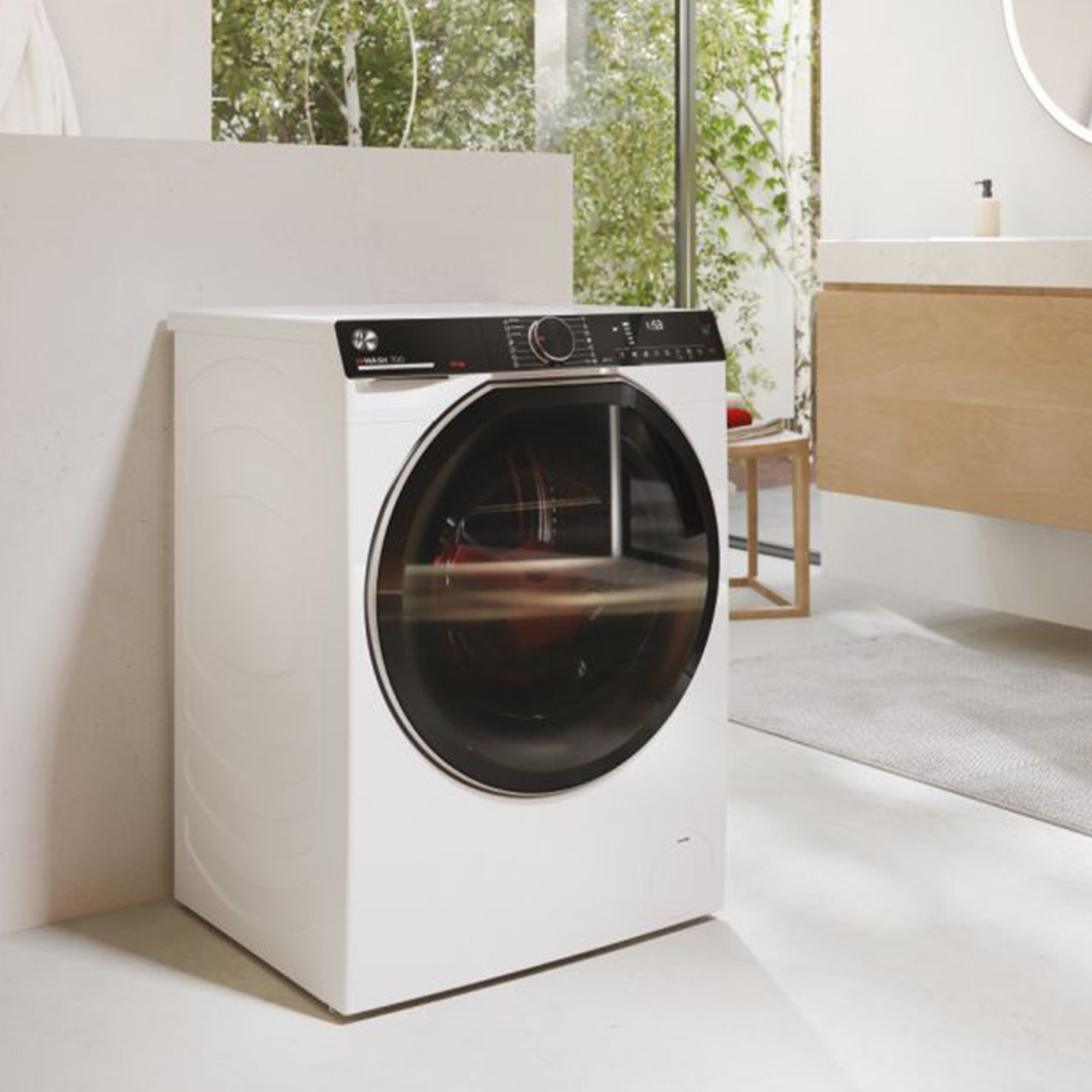 Eine weiße Waschmaschine in einem Badezimmer mit Spiegel.