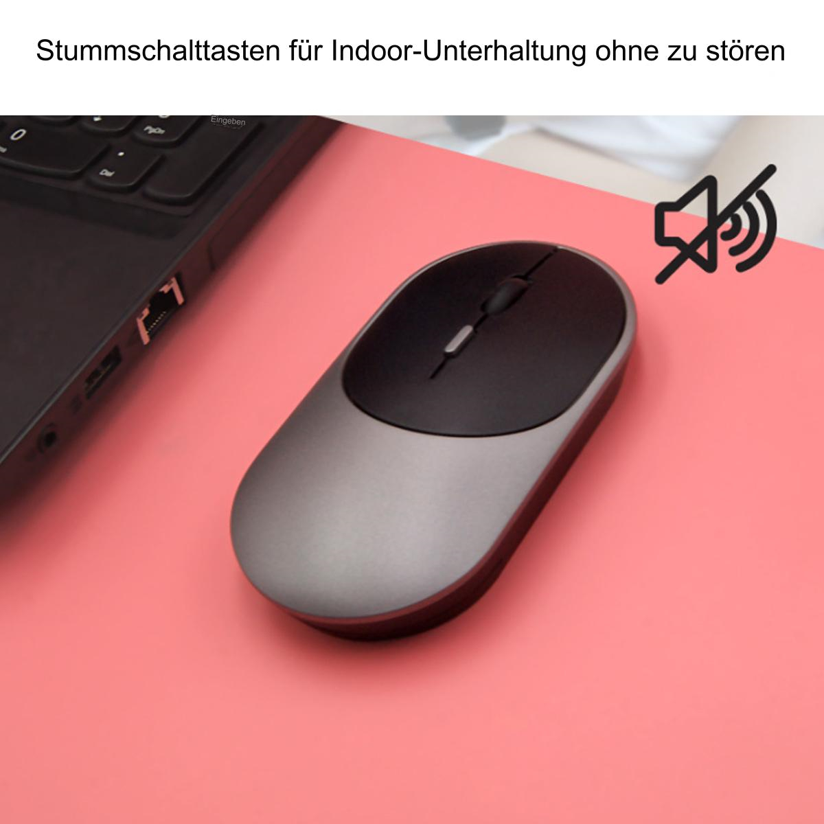 Eine grau-schwarze Maus liegt auf einer rosa Oberfläche. Ein Laptop ist links sichtbar.