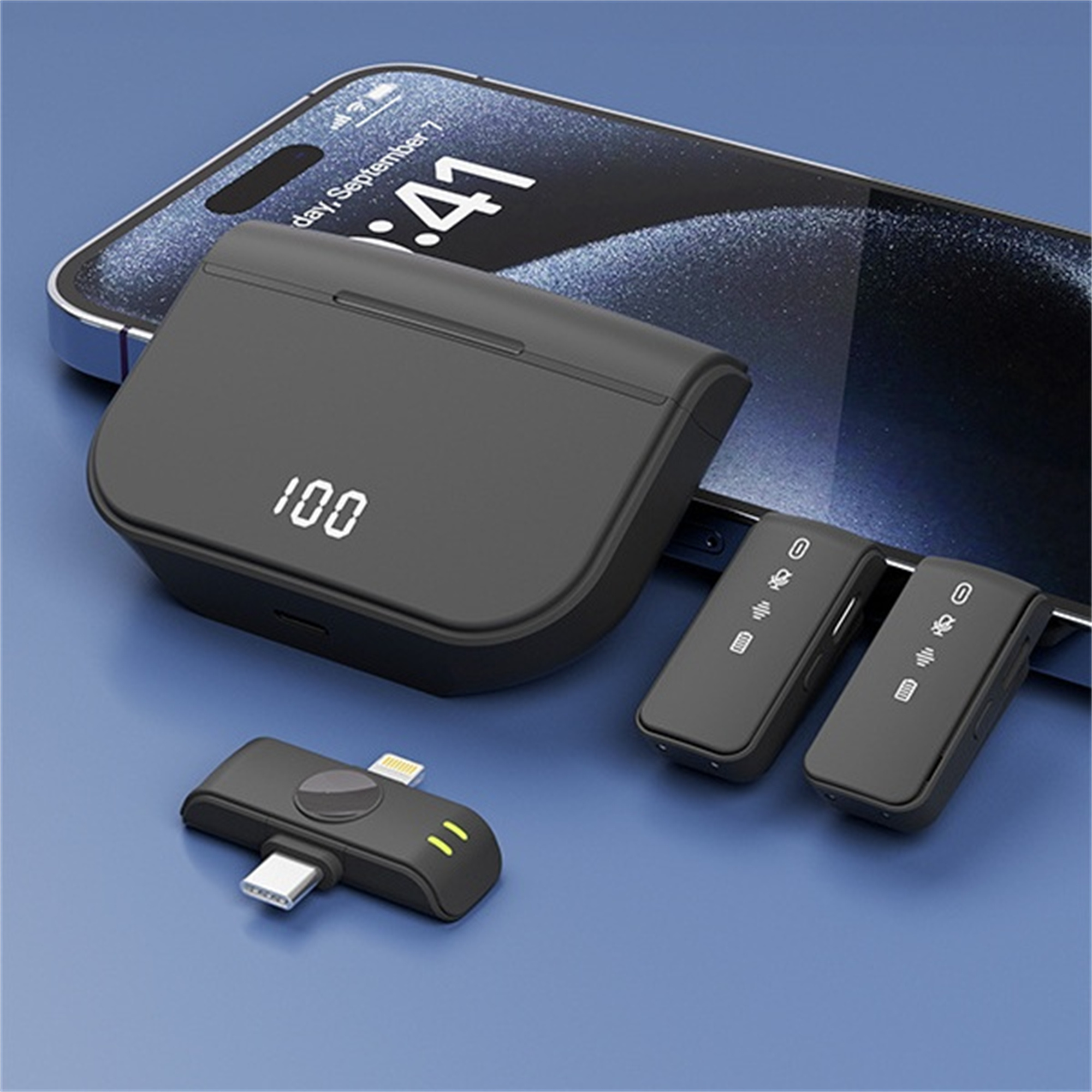 Schwarze Ladestation, Telefon, zwei drahtlose Mikrofone und ein USB-C-Adapter.