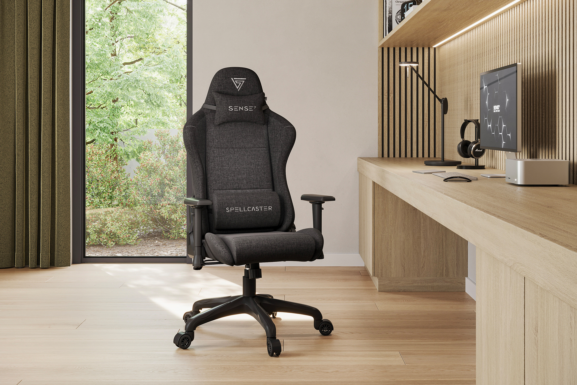 Gamingstoel in een kamer. Hij is donkergrijs met een hoofdsteun. Erachter staan een bureau en een raam.