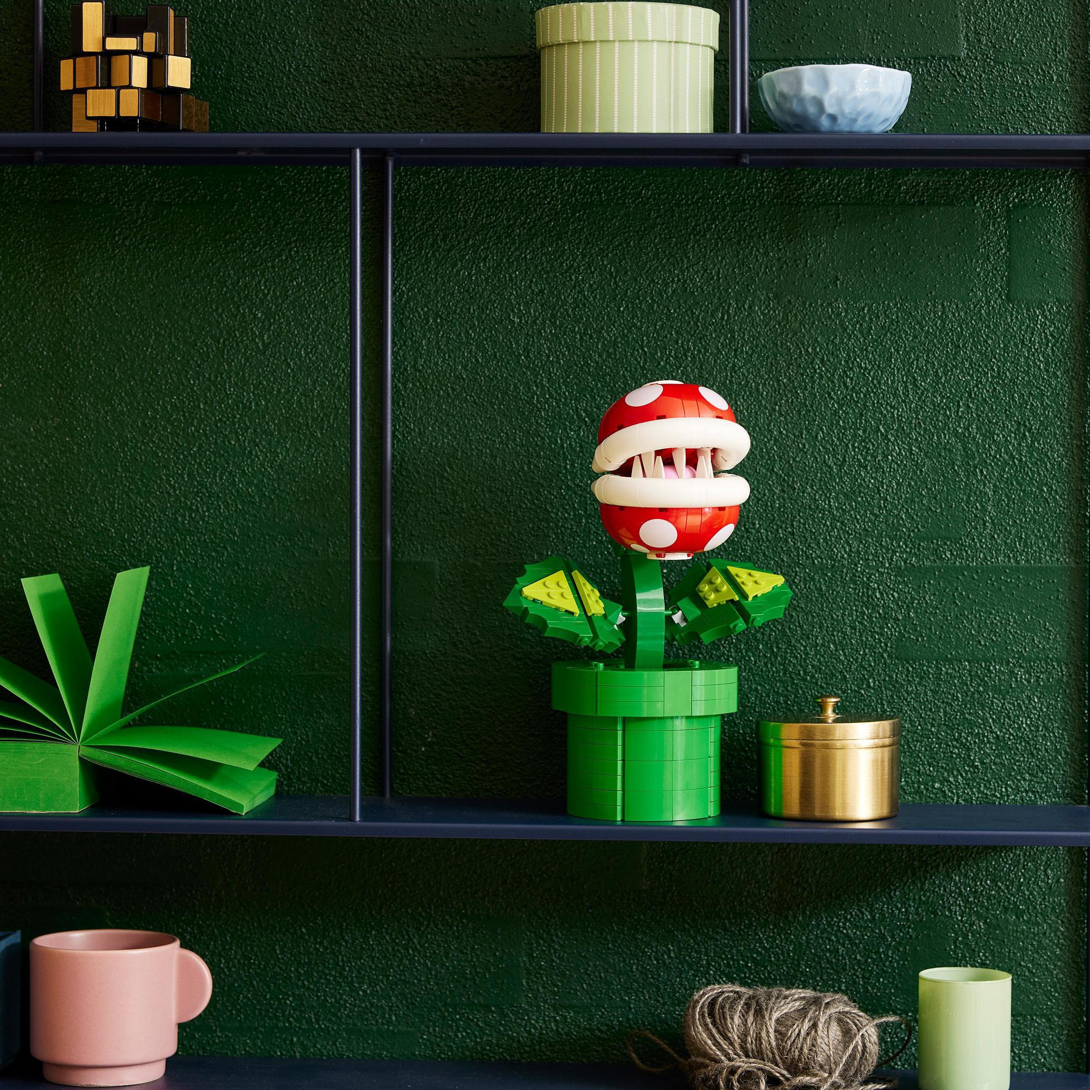 Una pianta Piranha Lego con testa rossa e bianca in un vaso verde.