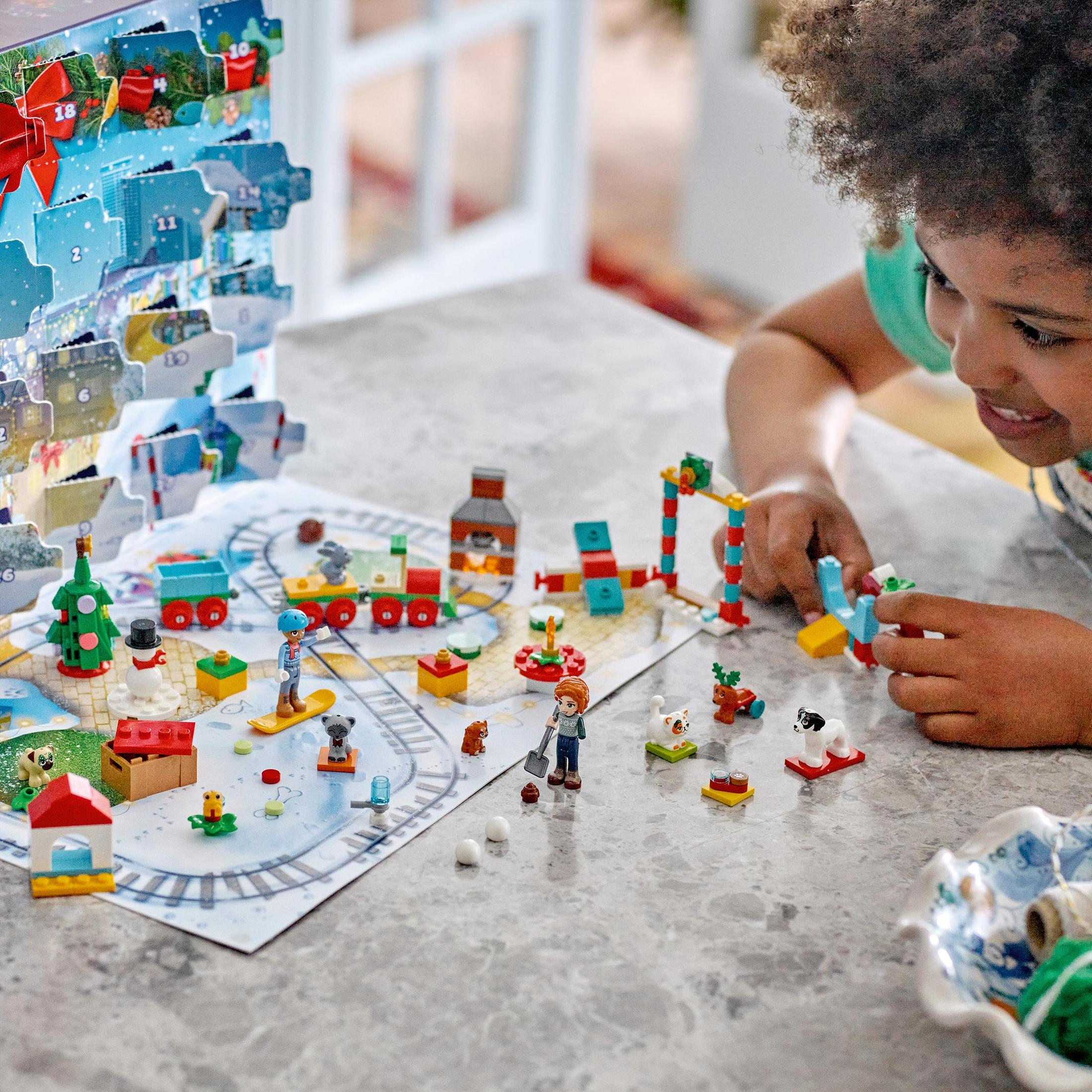 Een kind speelt met Lego-blokken en bouwt een kerstscène met een trein.