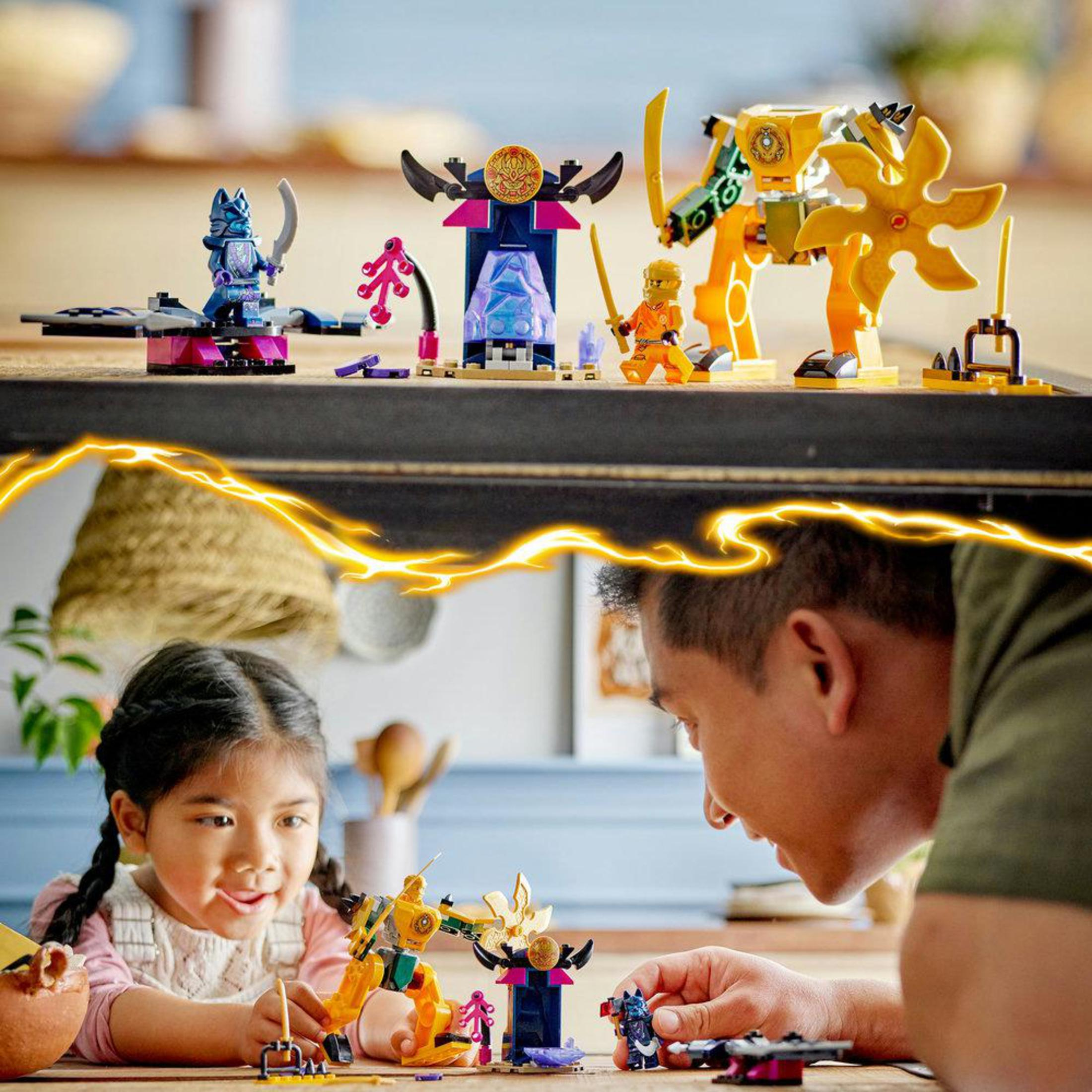 Een kind en een man spelen met een LEGO Ninjago set. Er zijn LEGO figuren en structuren.
