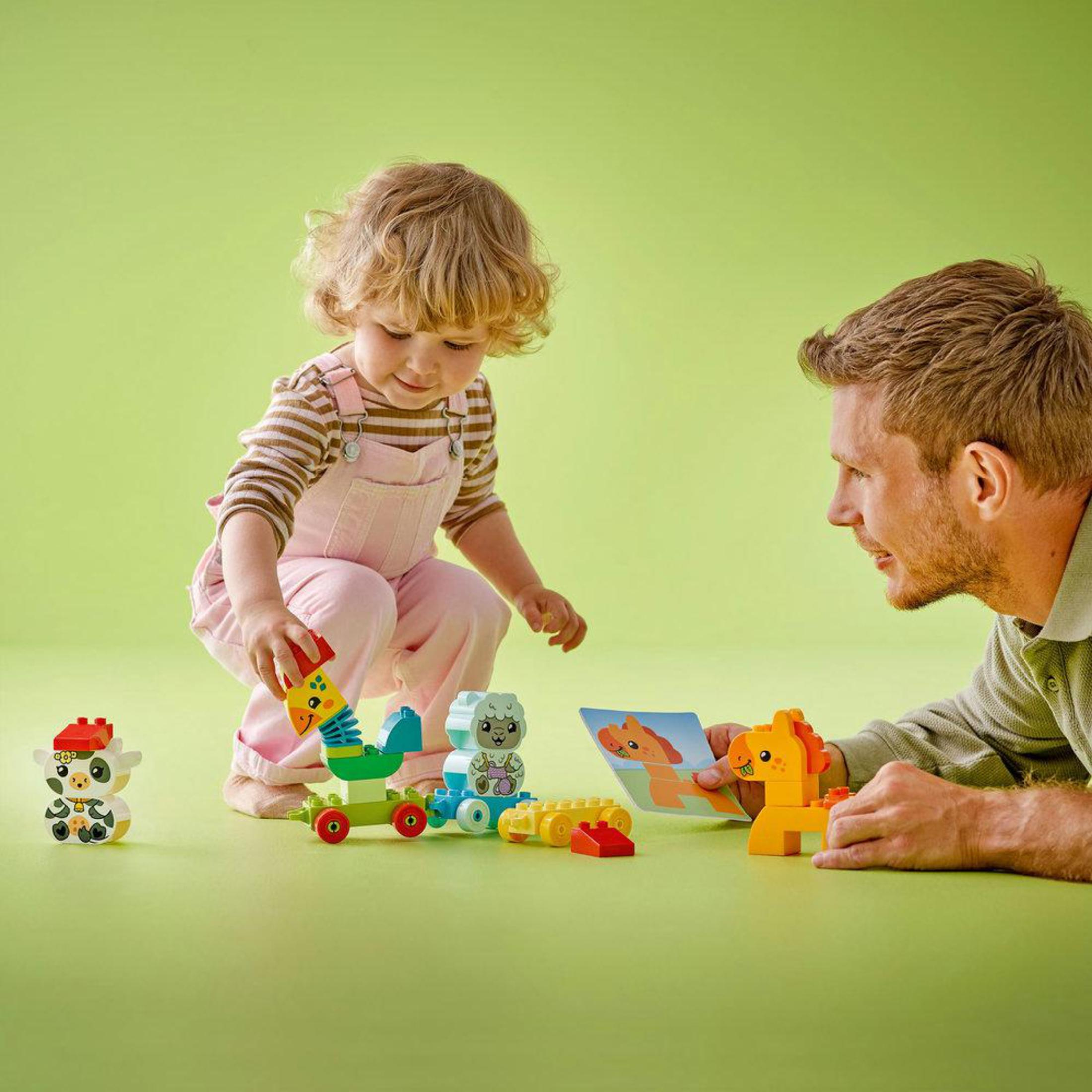Dziecko bawi się klockami. Mężczyzna patrzy. Zabawki są umieszczone na zielonej powierzchni.