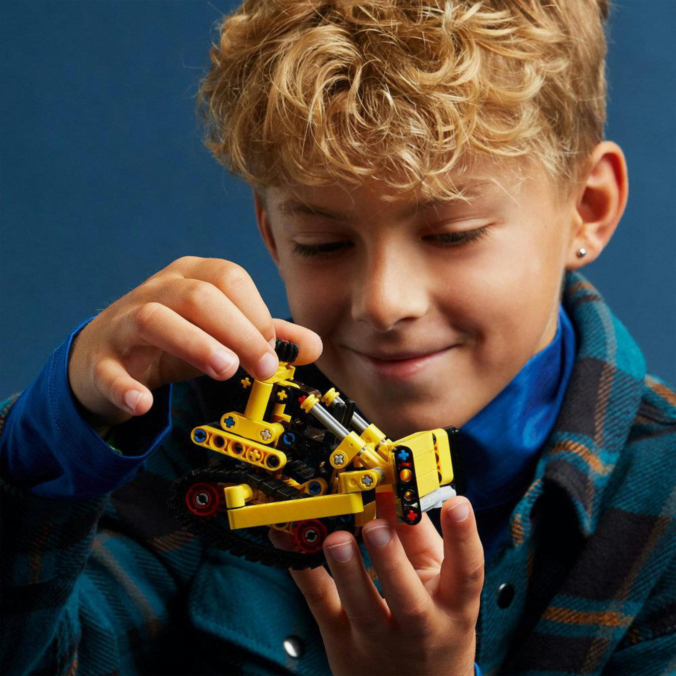 Un ragazzino che tiene in mano un giocattolo da costruzione Lego, sorridendo alla fotocamera.