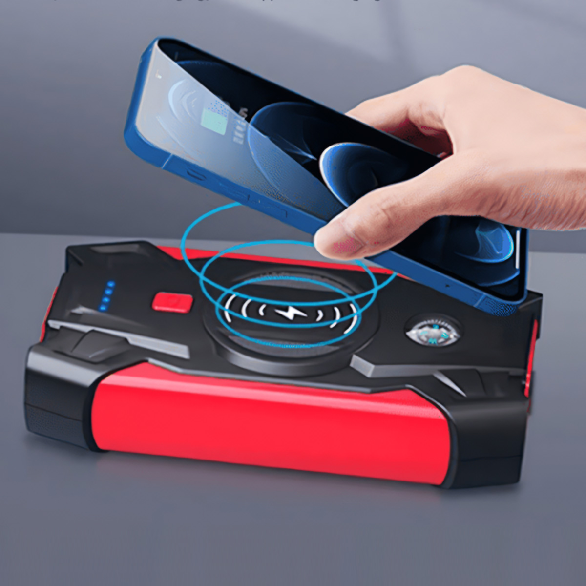 Una mano sosteniendo un teléfono azul sobre un cargador portátil rojo y negro con un icono de carga.