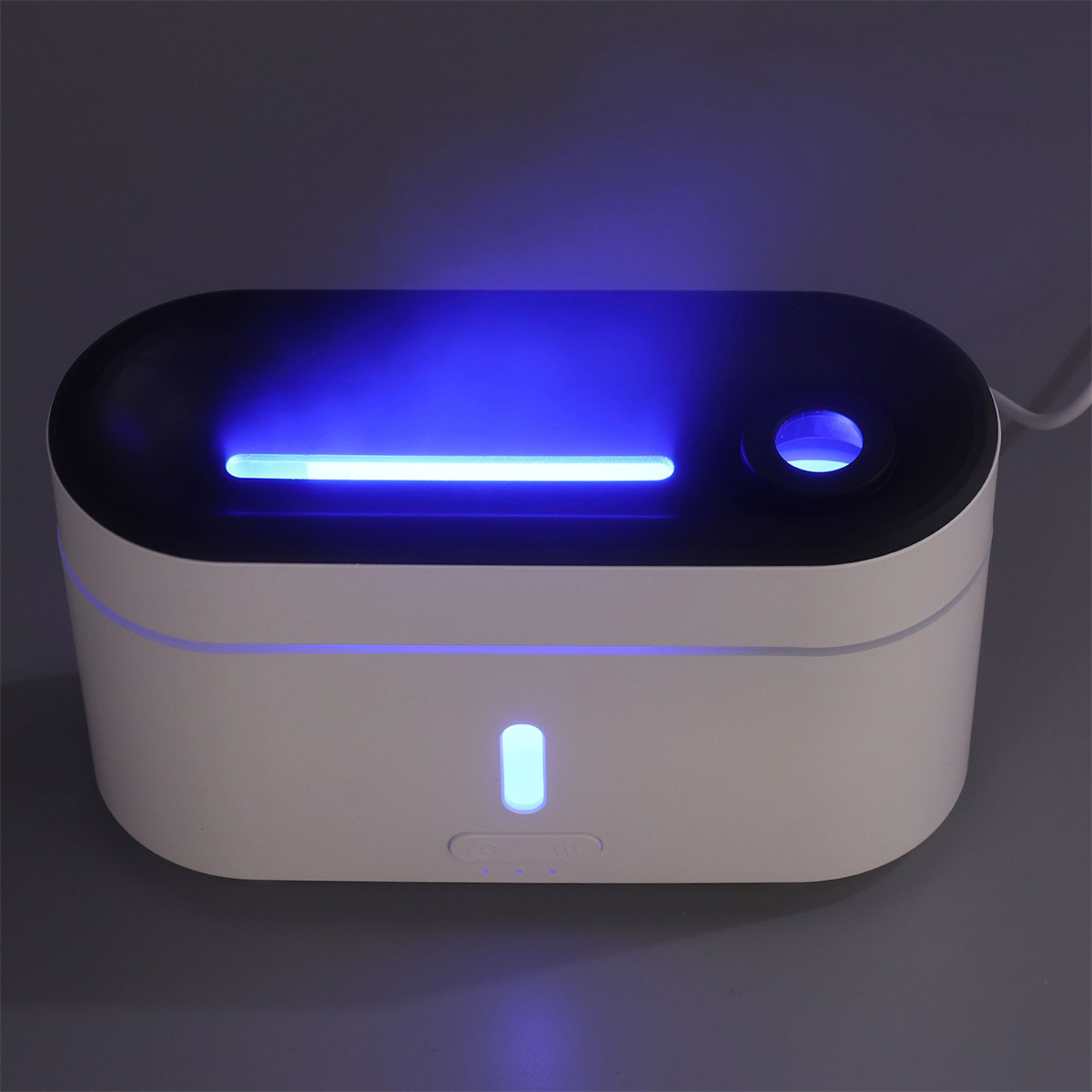 Ein weiß-blauer Sterilisator mit blauem Licht im Inneren auf grauer Fläche.