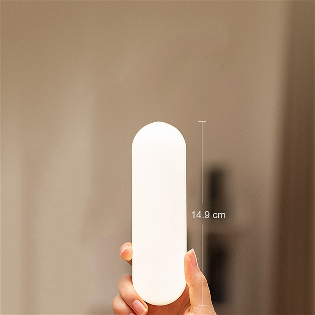 Weiße, beleuchtete, zylindrische Lampe, mit einer Hand, die sie hält.