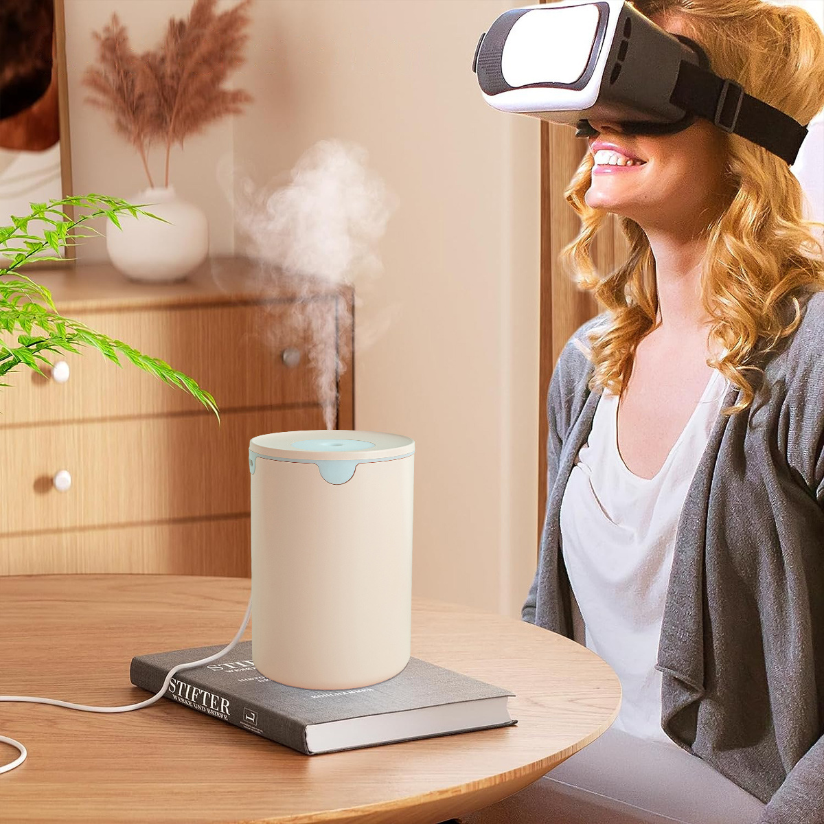 Frau benutzt VR-Headset. Ein Luftbefeuchter steht auf einem Tisch mit einem Buch. Die Szene hat weiches Licht.