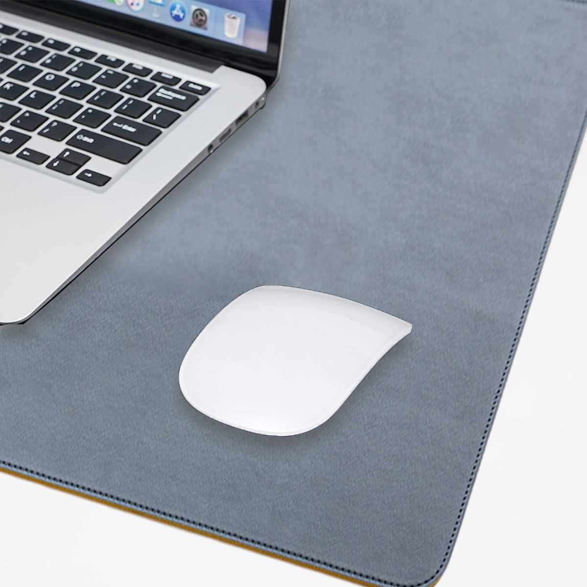 Ein Laptop und eine weiße Maus auf einer grauen Schreibtischunterlage mit gelbem Rand, weißer Hintergrund.