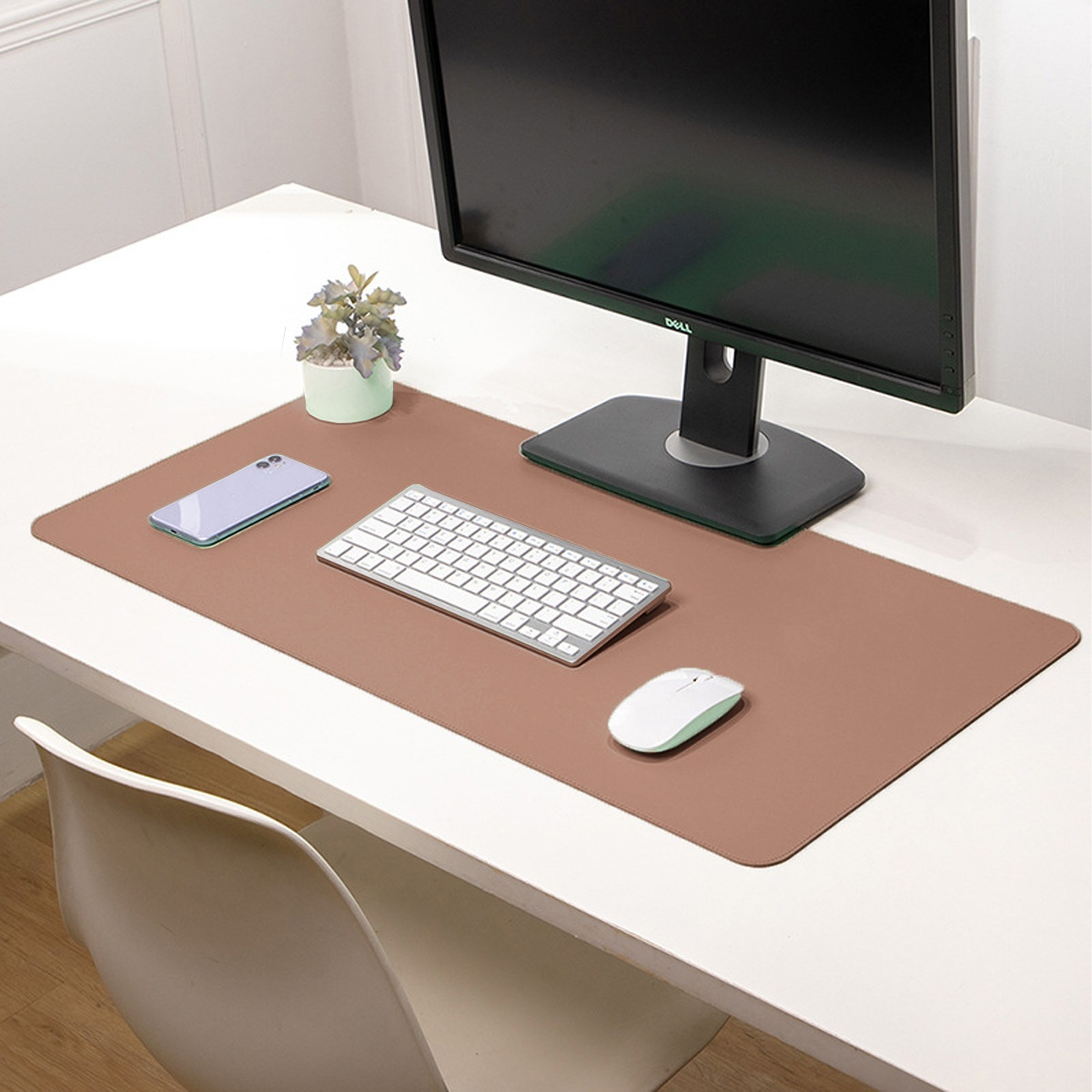 Schreibtisch mit Mauspad, Tastatur, Telefon und Monitor. Weiße Schreibtischoberfläche.