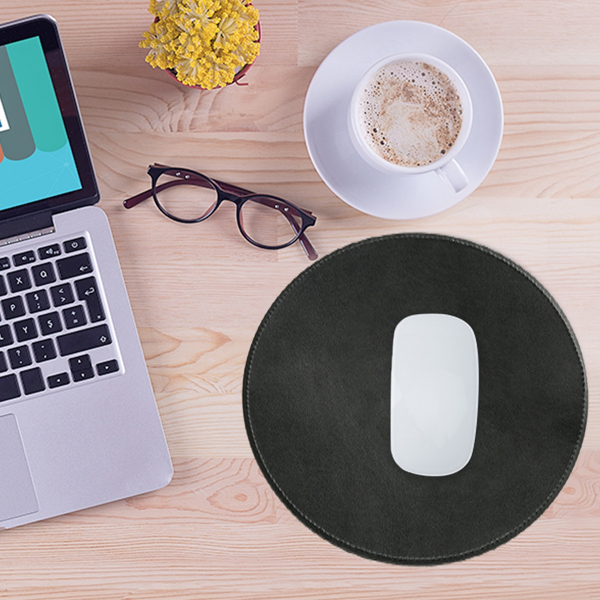 Laptop, Maus, Brille und Kaffeetasse auf einem Holzschreibtisch.