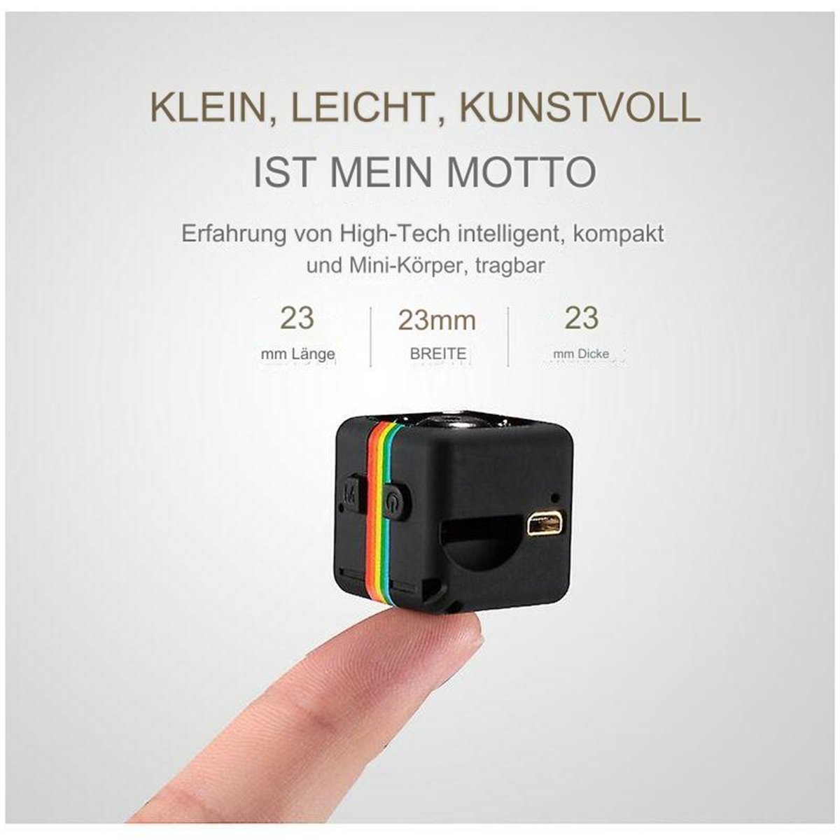 Kleine schwarze Kamera mit Regenbogenstreifen, gehalten von einem Finger, auf weißem Hintergrund.