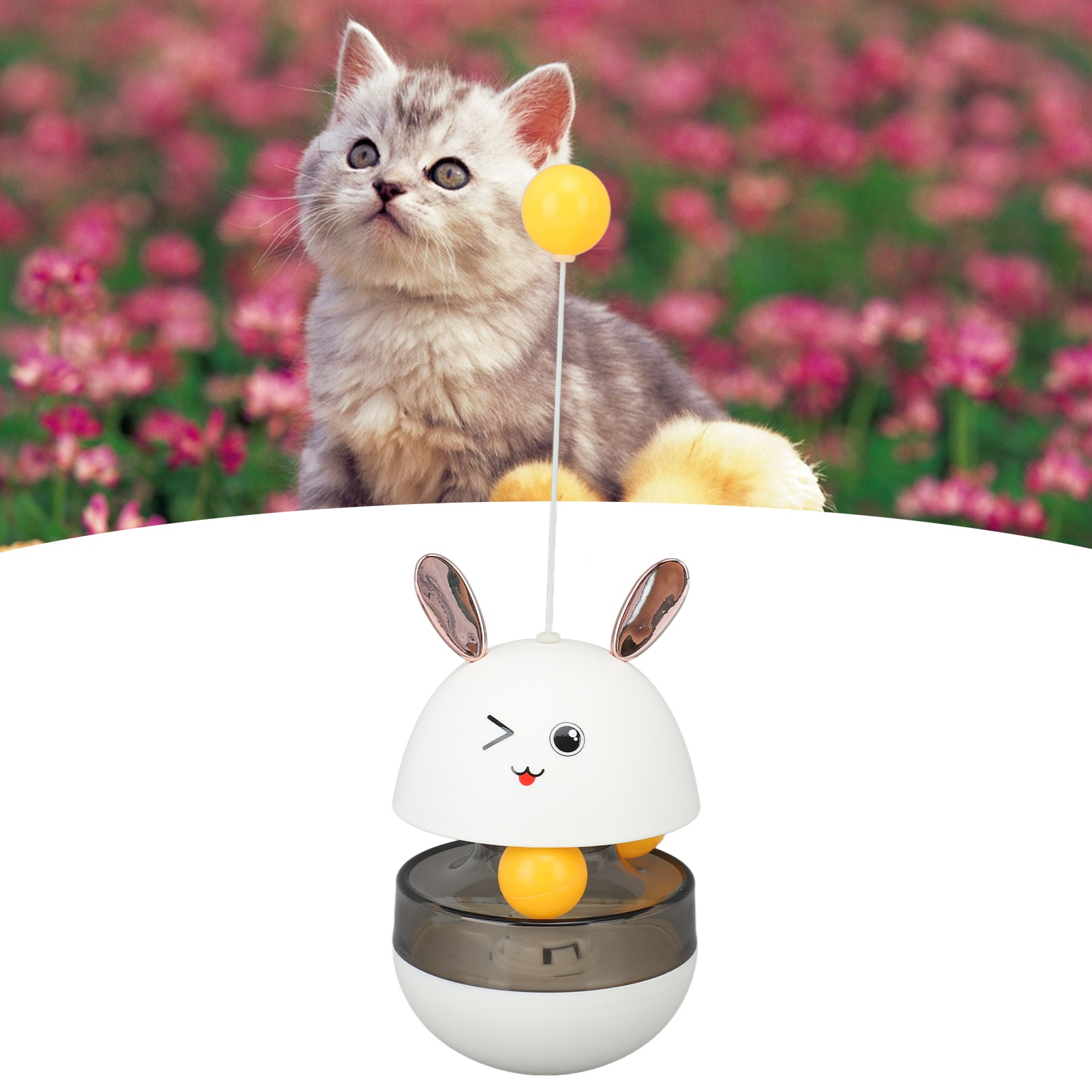 Eine Katze blickt auf ein gelbes Ballspielzeug. Ein Spielzeug in Hasenform mit gelbem Ball ist im Vordergrund.