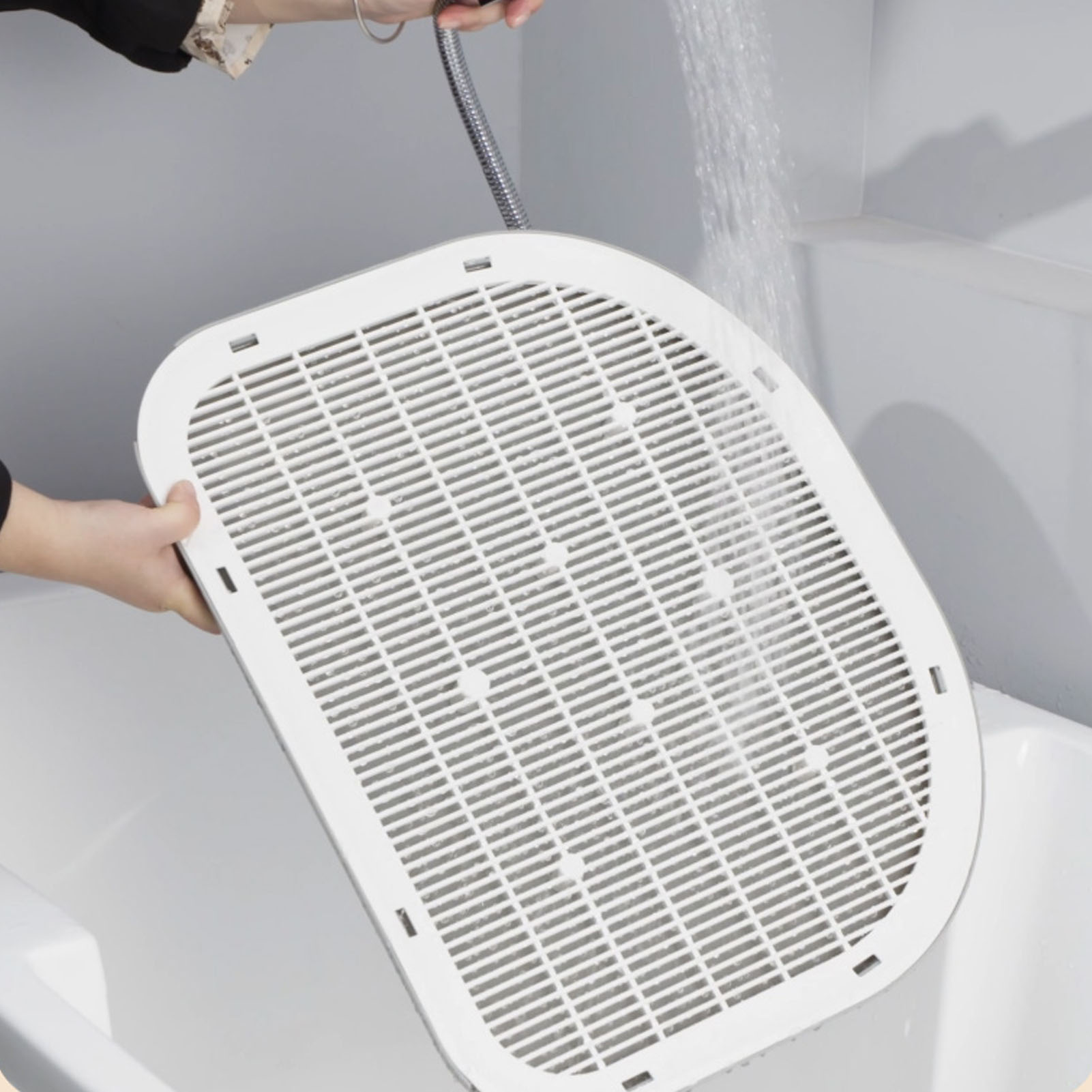Ein Tablett wird mit Wasser gereinigt. Weißes Tablett mit weißem Gitter wird in einer weißen Wanne gewaschen.