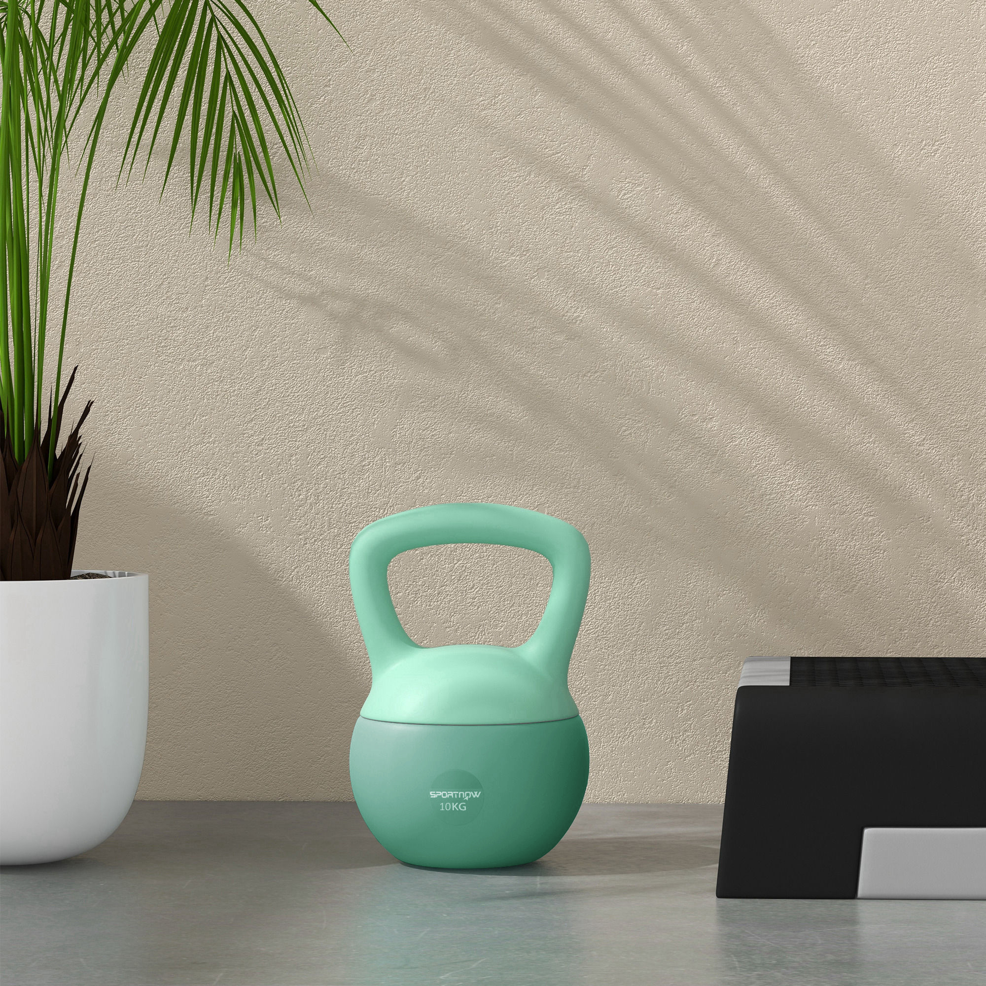 Kettlebell verde y menta sobre una superficie gris, con una planta y un banco de pesas negro.