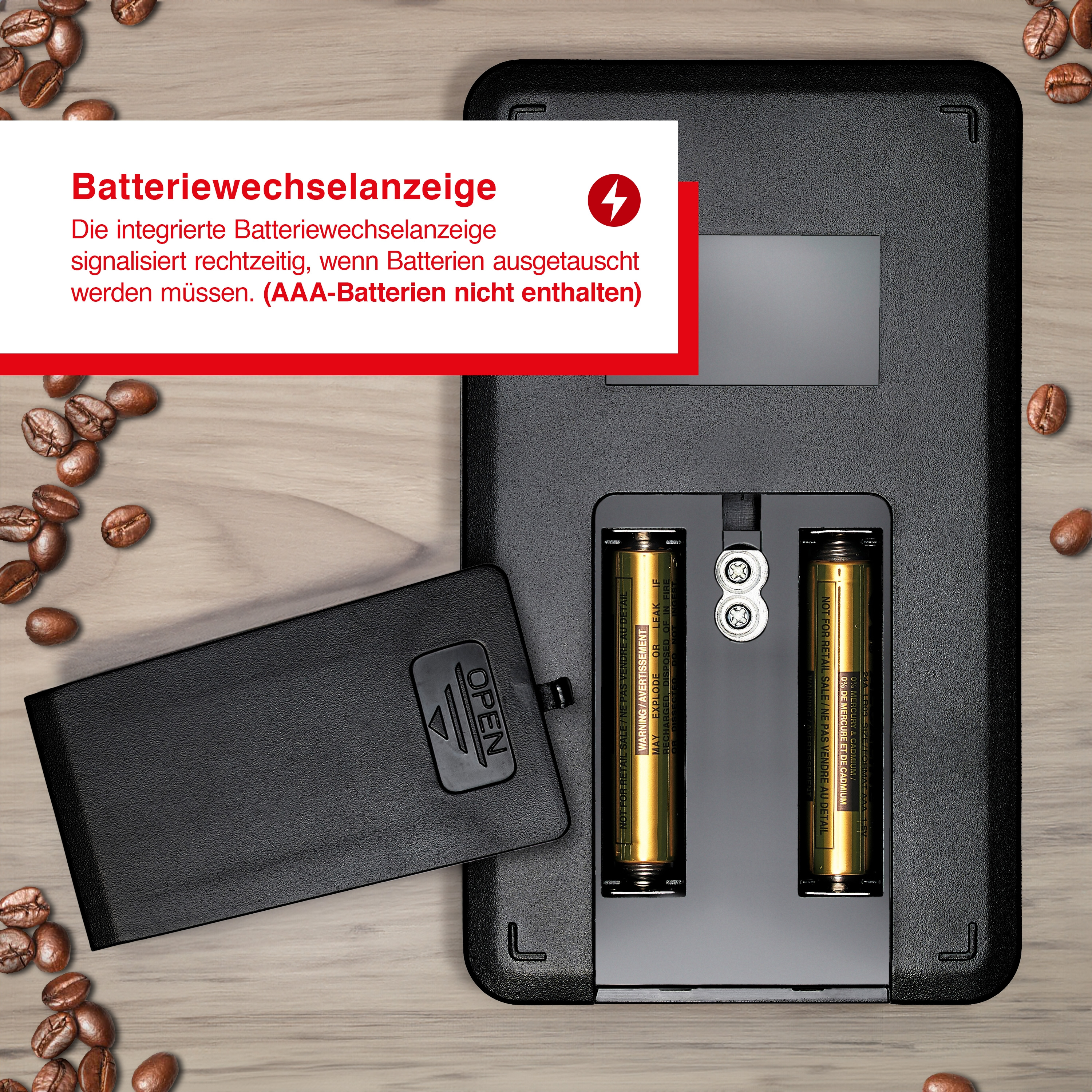 Waage mit Batterien, Text zum Batteriewechsel und Kaffeebohnen drumherum.