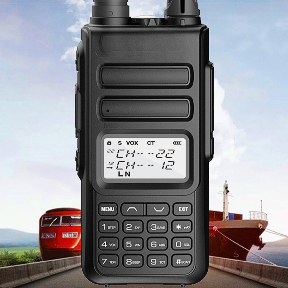Schwarzes Walkie-Talkie mit Bildschirm und Knöpfen. Es steht auf einer Straße mit Zug und Boot im Hintergrund.