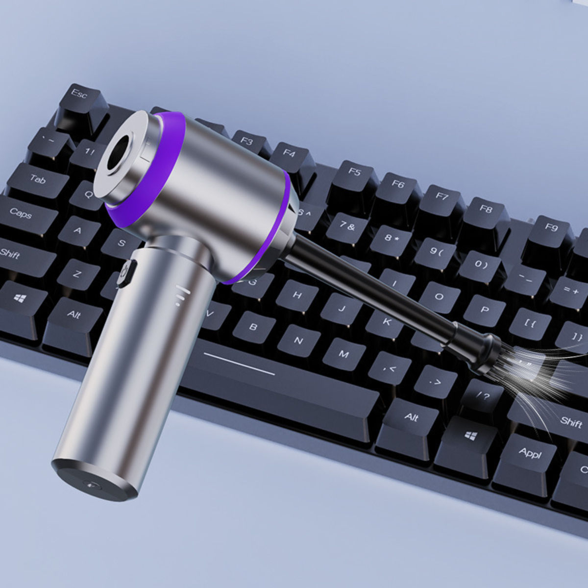 Silberner und violetter Tastaturreiniger, der Staub von schwarzen Tastaturtasten bläst.
