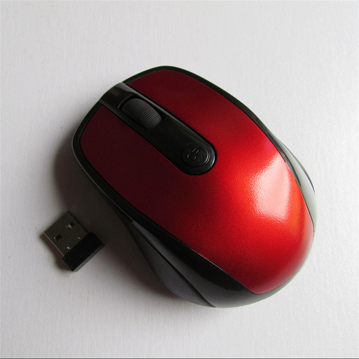 Eine rot-schwarze Computermaus mit einem USB-Empfänger daneben, auf weißem Untergrund.