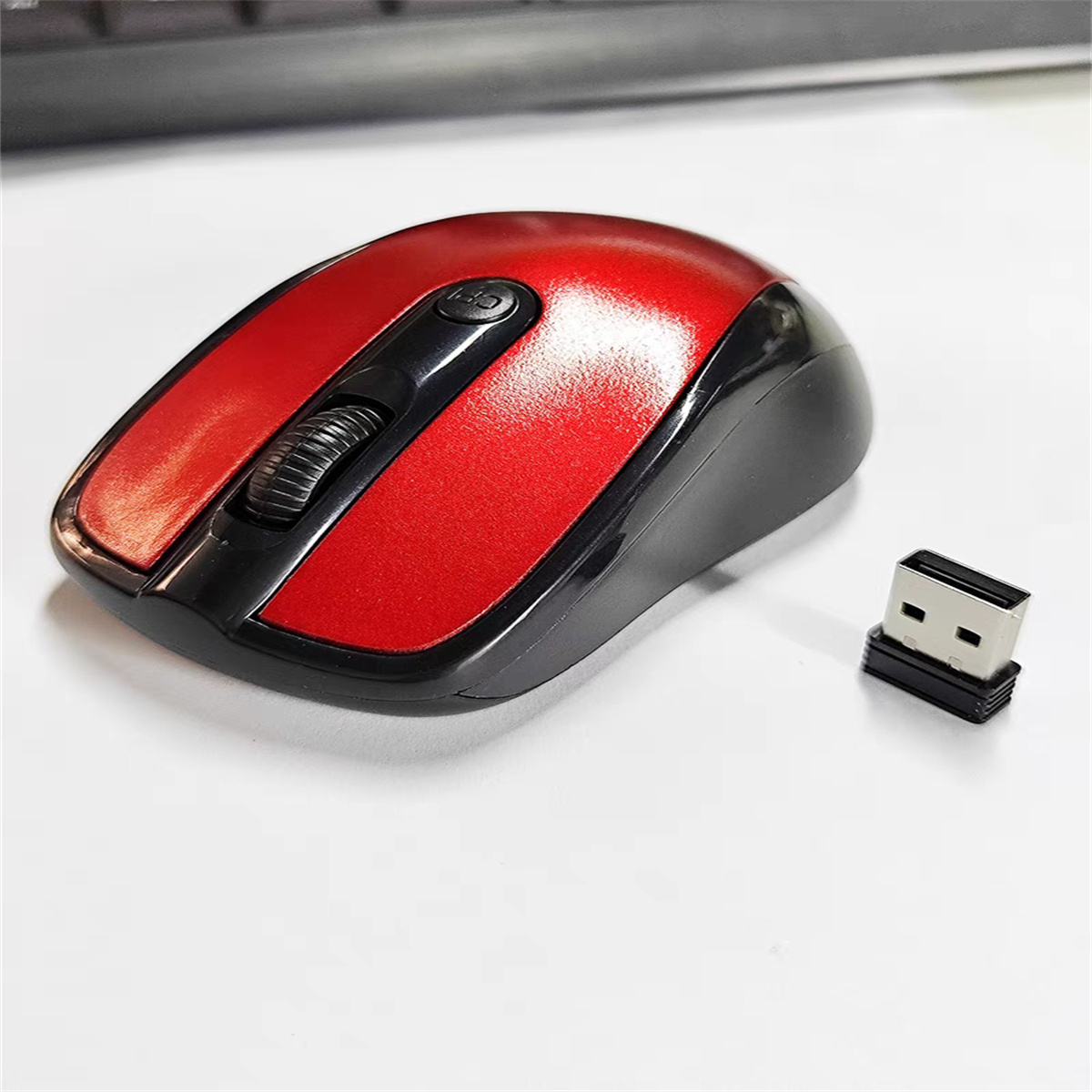 Eine rot-schwarze kabellose Maus und ein USB-Empfänger auf weißer Oberfläche. Schwarzer Hintergrund.