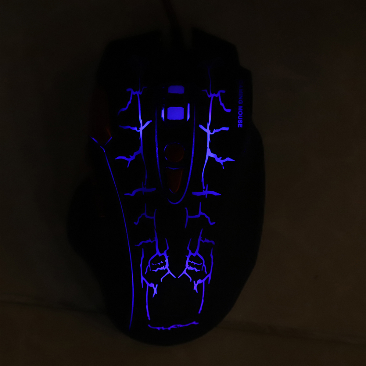 Eine schwarze Gaming-Maus leuchtet mit blauen Linien und einem roten Knopf. Die Maus leuchtet im Dunkeln.