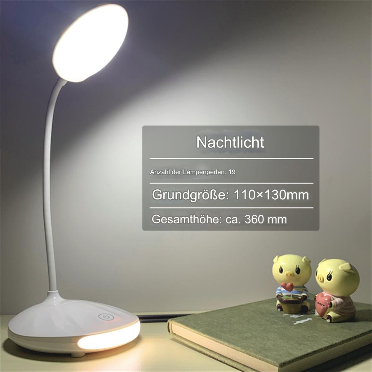 Eine weiße Schreibtischlampe und zwei Schweinchenfiguren auf einem Schreibtisch.
