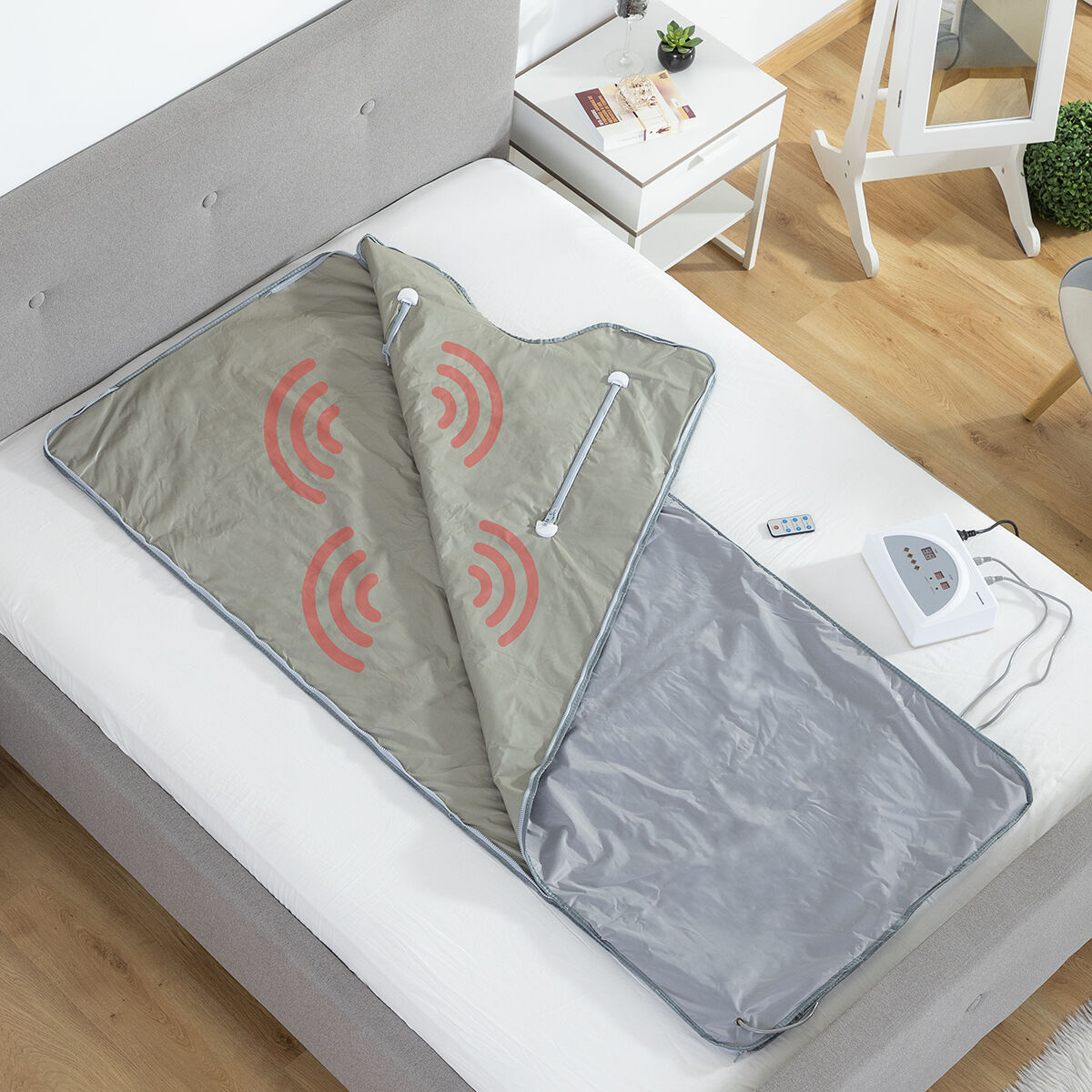 Coperta termica grigia su un letto. Cerchi rossi indicano le zone di calore. Sfondo bianco.