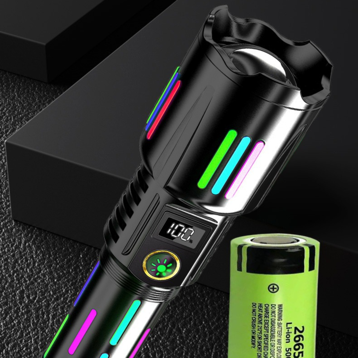 Schwarze Taschenlampe mit bunten Lichtern. Eine grüne Batterie liegt daneben. Dunkler Hintergrund.