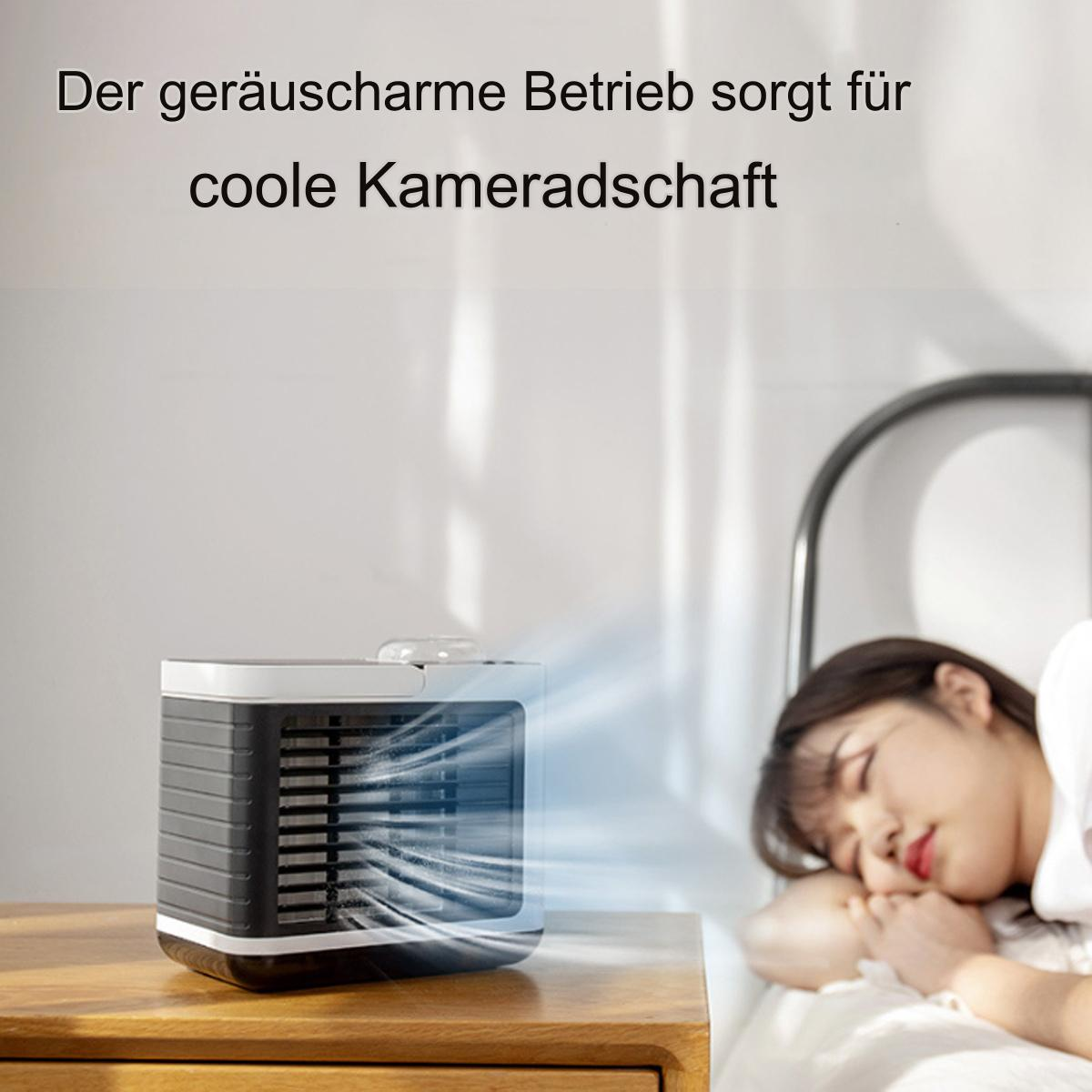 Luftkühler auf einem Nachttisch, mit einer schlafenden Frau im Bett im Hintergrund.