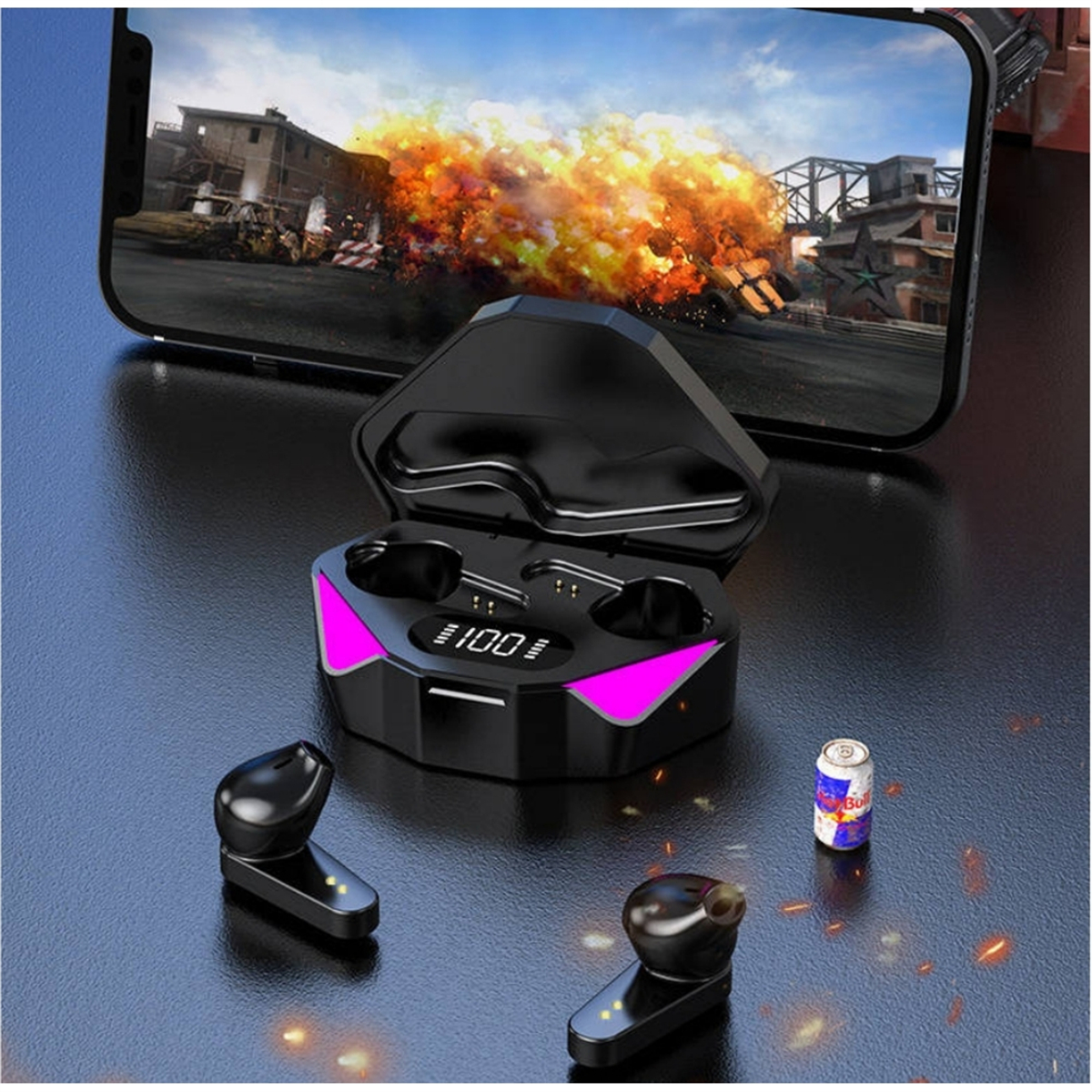 Schwarze Gaming-Ohrhörer in einem Ladecase, Telefon, das ein Spiel anzeigt, und eine Red Bull-Dose.