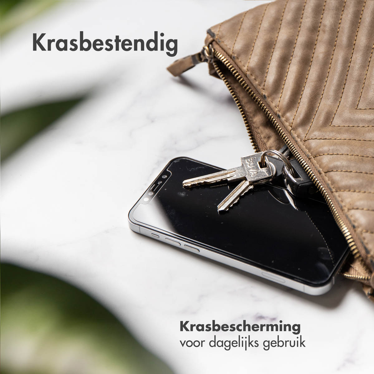 Een smartphone en sleutels in een bruine tas op een marmeren oppervlak.