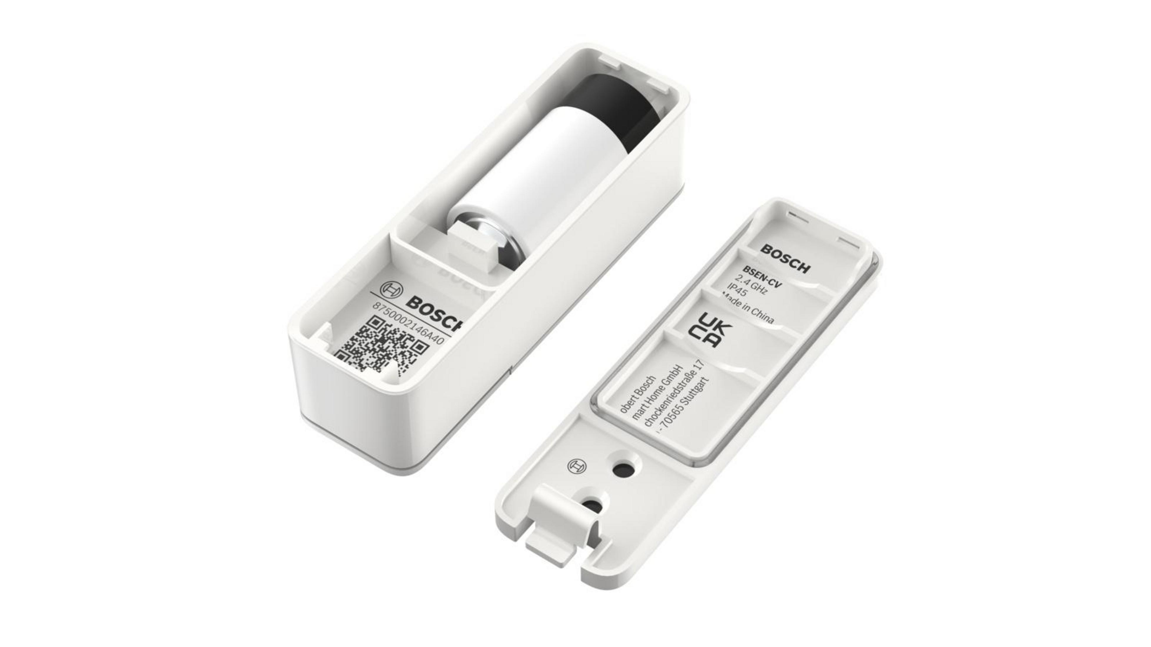 Białe prostokątne urządzenie z baterią w środku i pokrywą. Tekst na urządzeniu i pokrywie.