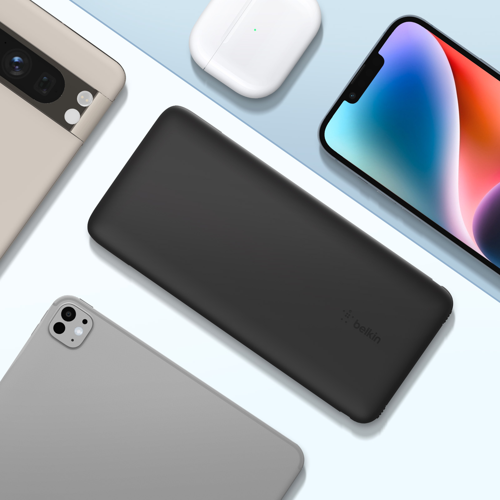 Eine schwarze Powerbank, ein beiges Telefon, ein graues Tablet und ein weißes AirPods-Case auf blauer Oberfläche.