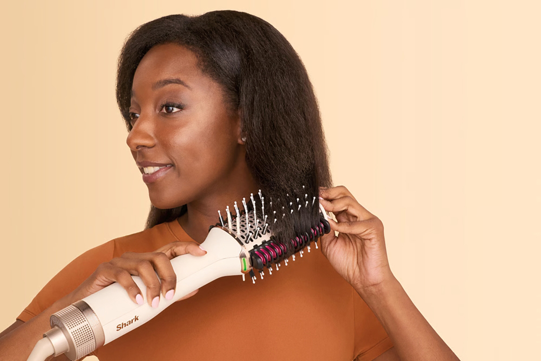 Kobieta szczotkująca włosy za pomocą białego i czarnego narzędzia do stylizacji włosów.