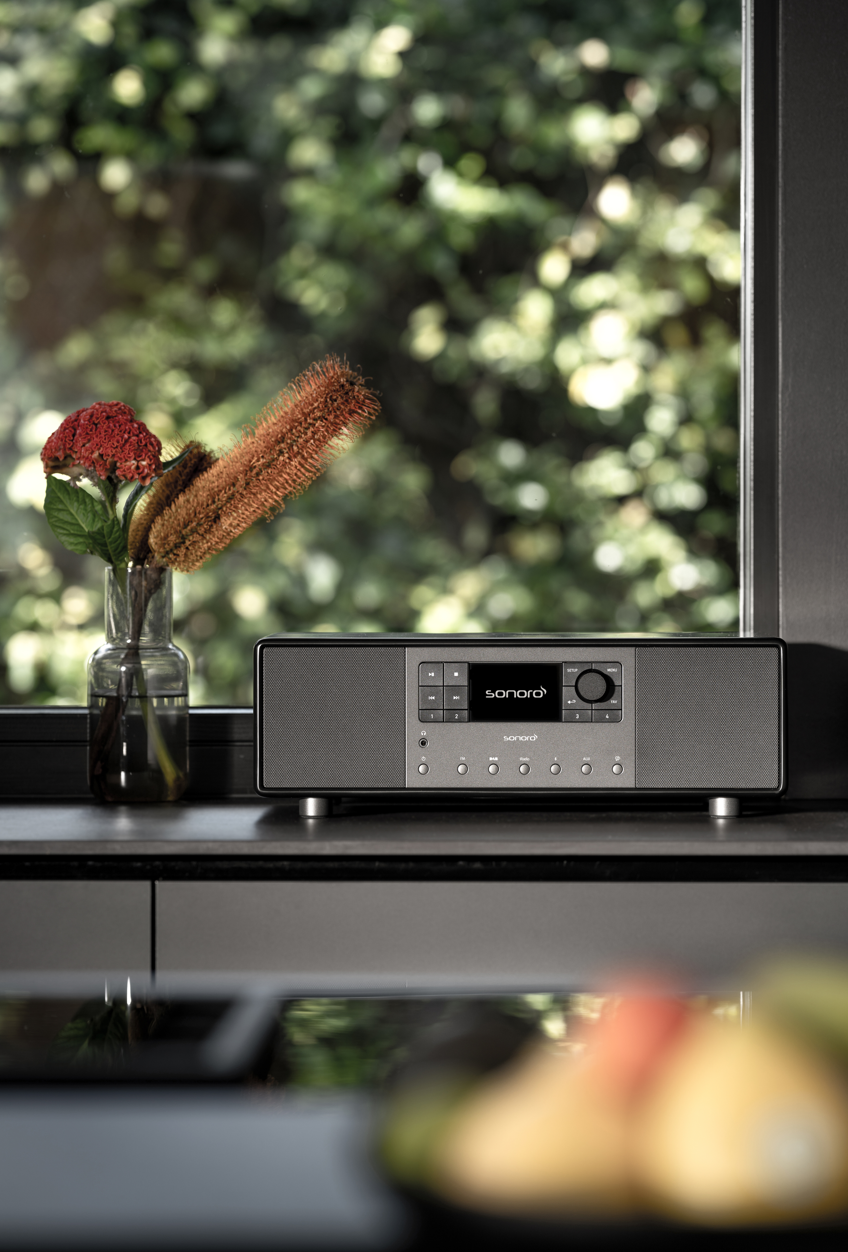Zilveren smart radio op een aanrecht. Bloemen en raam op de achtergrond.