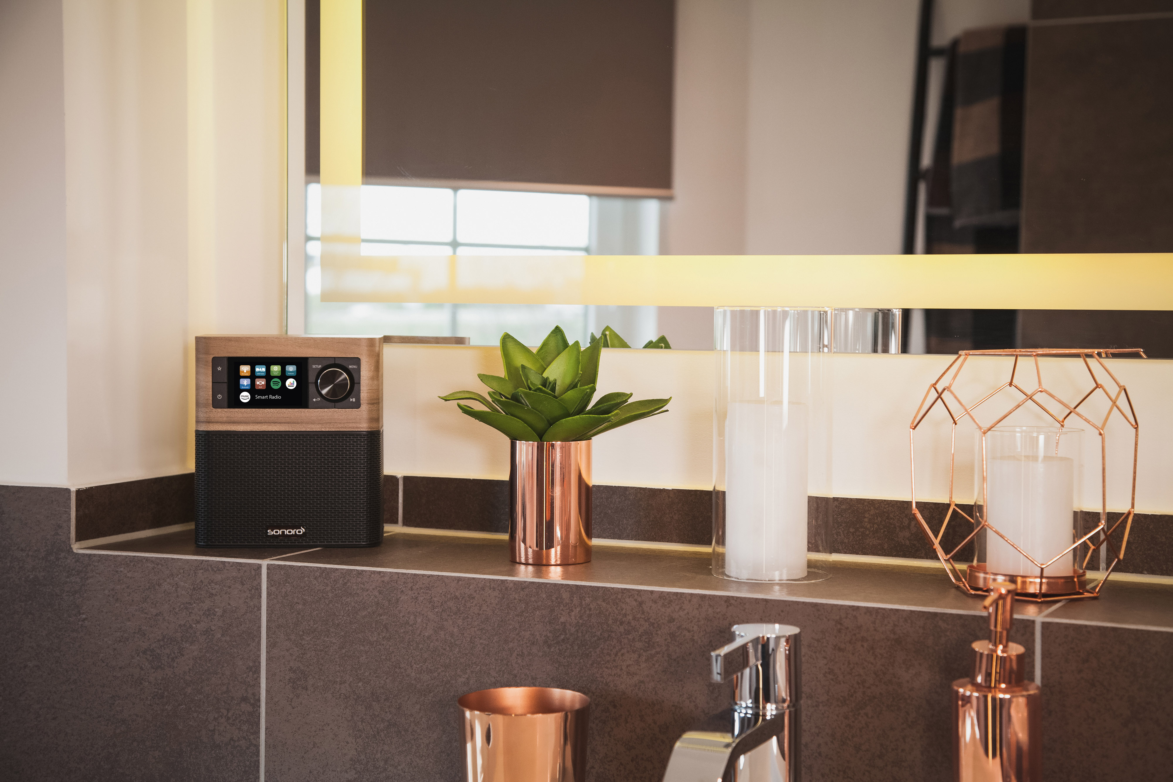 Sonoro-Radio auf Regal im Badezimmer. Spiegel darüber. Kupferakzente.