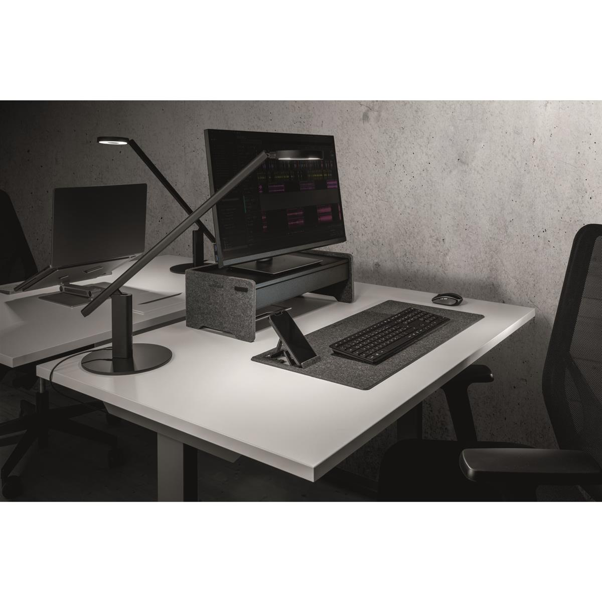 Espace de travail avec moniteur, clavier, téléphone et deux lampes. Une configuration de bureau moderne et minimaliste.