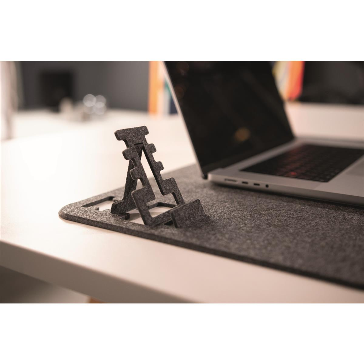 Support d'ordinateur portable noir, ordinateur portable noir, sur un coussinet en feutre gris, table blanche.