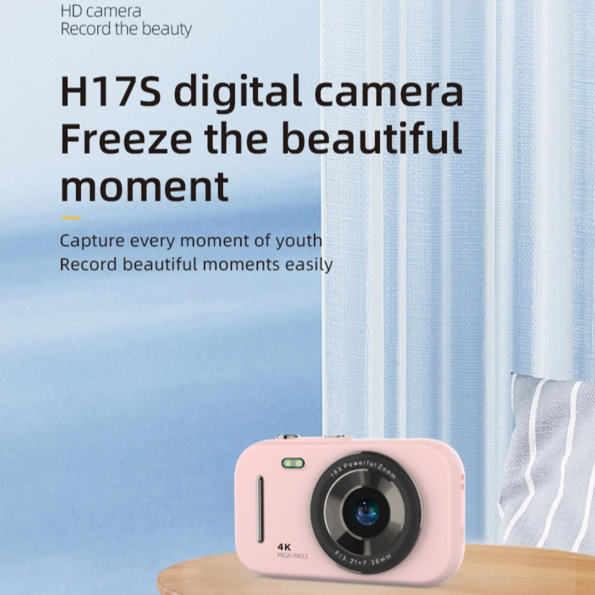 Rosa Digitalkamera auf einem Tisch, Text darüber. Der Hintergrund ist blauer Himmel und Kissen.