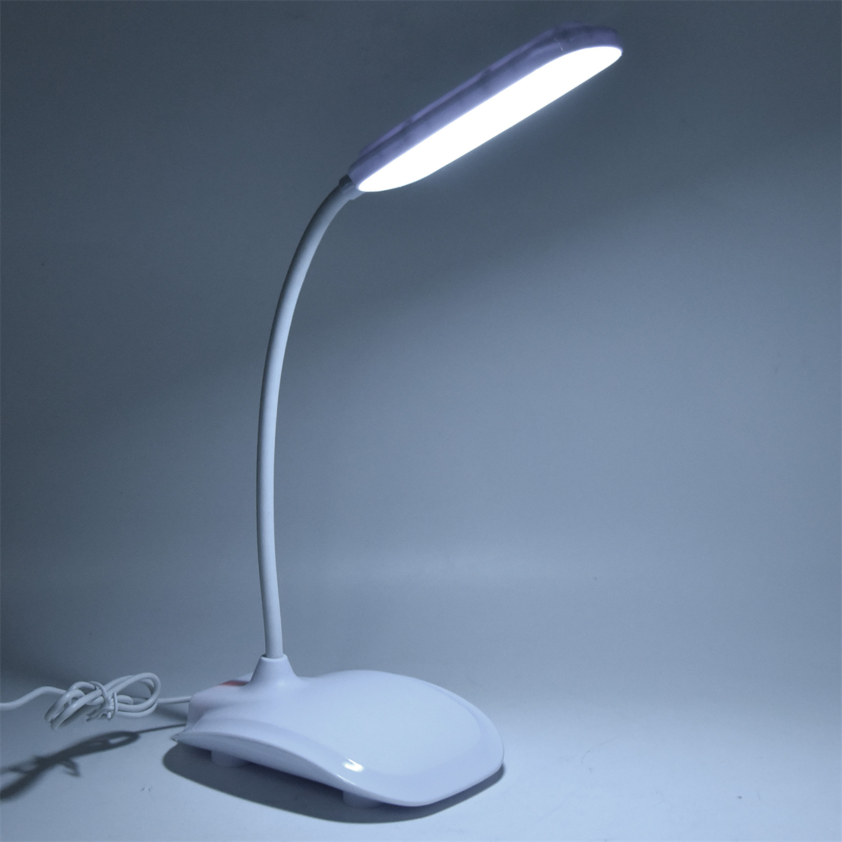 Weiße Schreibtischlampe mit flexiblem Hals. Die Lampe leuchtet und erzeugt ein weißes Leuchten.
