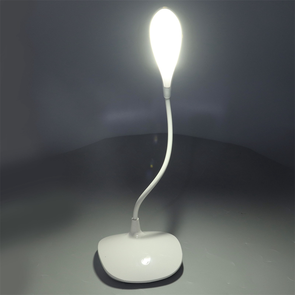 Eine weiße Schreibtischlampe mit gebogenem Hals und hellem Licht.