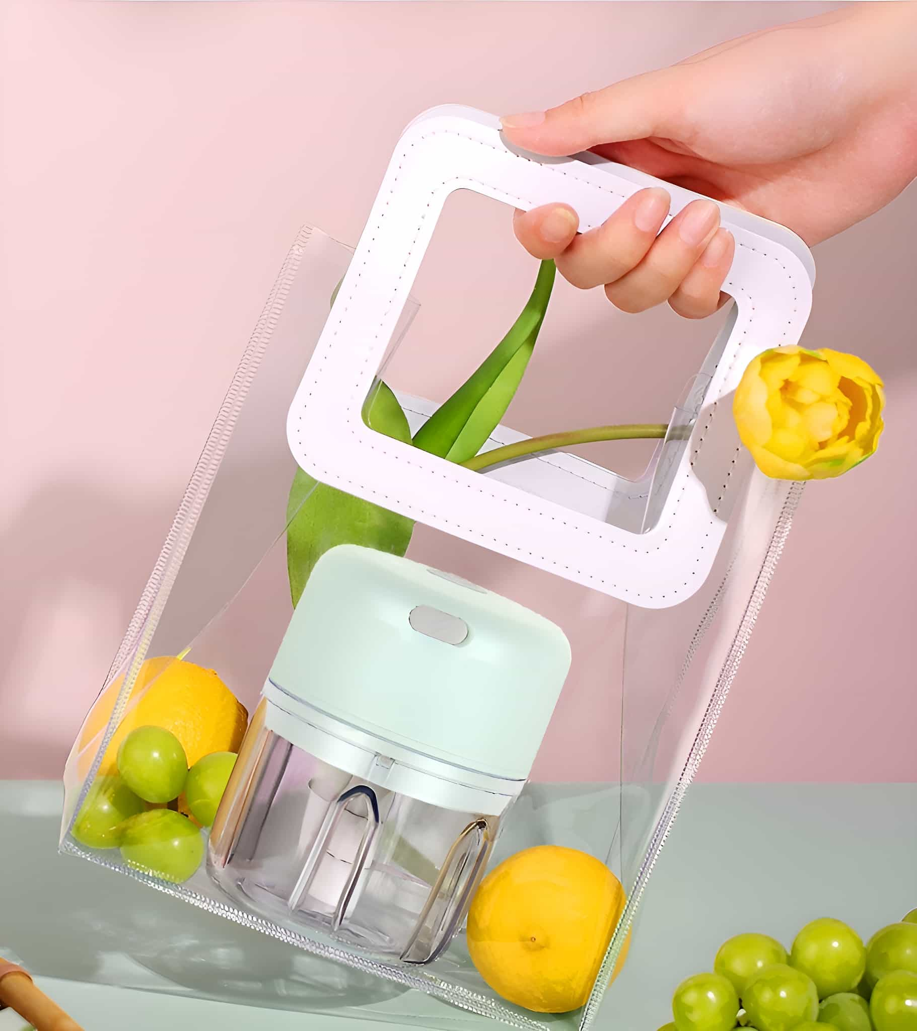 Hand hält transparente Tasche mit Mini-Küchenmaschine und Früchten.