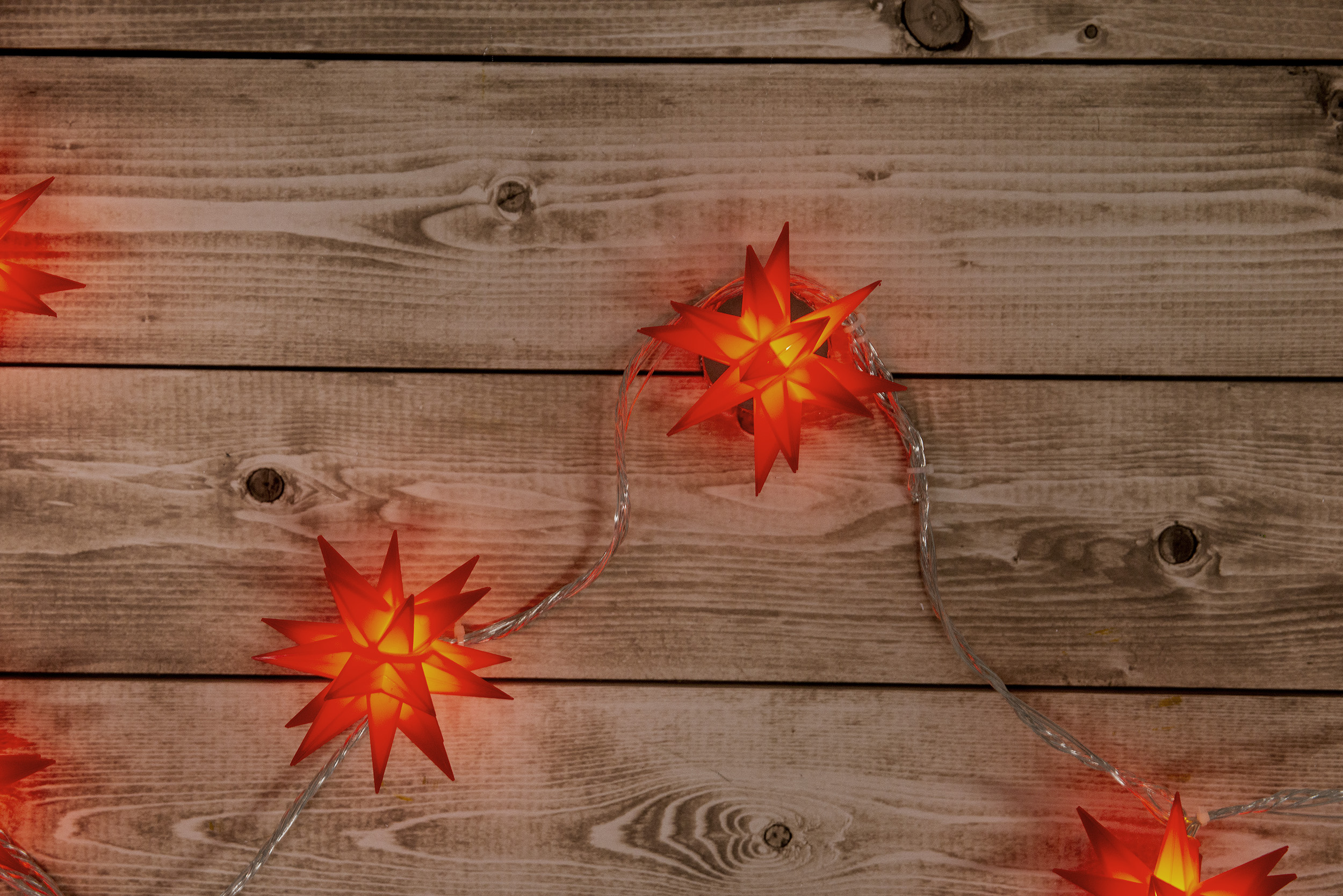 Draufsicht auf einen Holztisch mit sternförmigen Lichtern, die darüber gespannt sind.