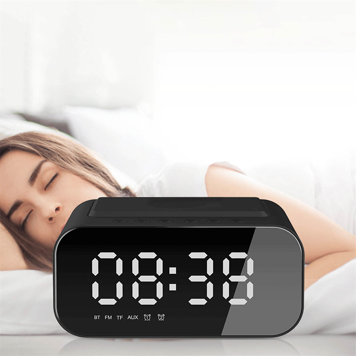 Schwarze Digitaluhr mit der Anzeige 08:38, neben einer schlafenden Frau im Bett.