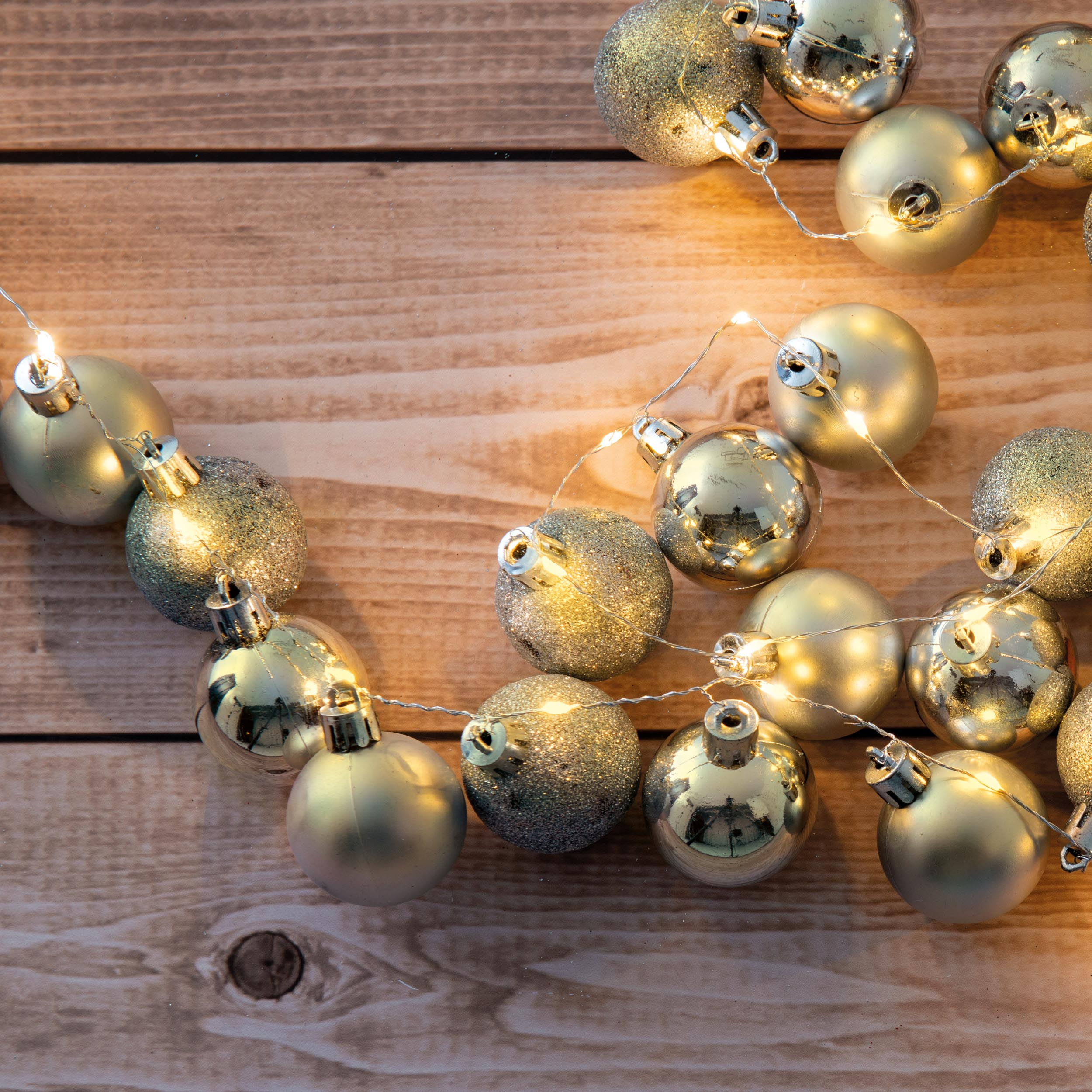 Weihnachtsschmuck und Lichterketten auf einer Holzoberfläche.